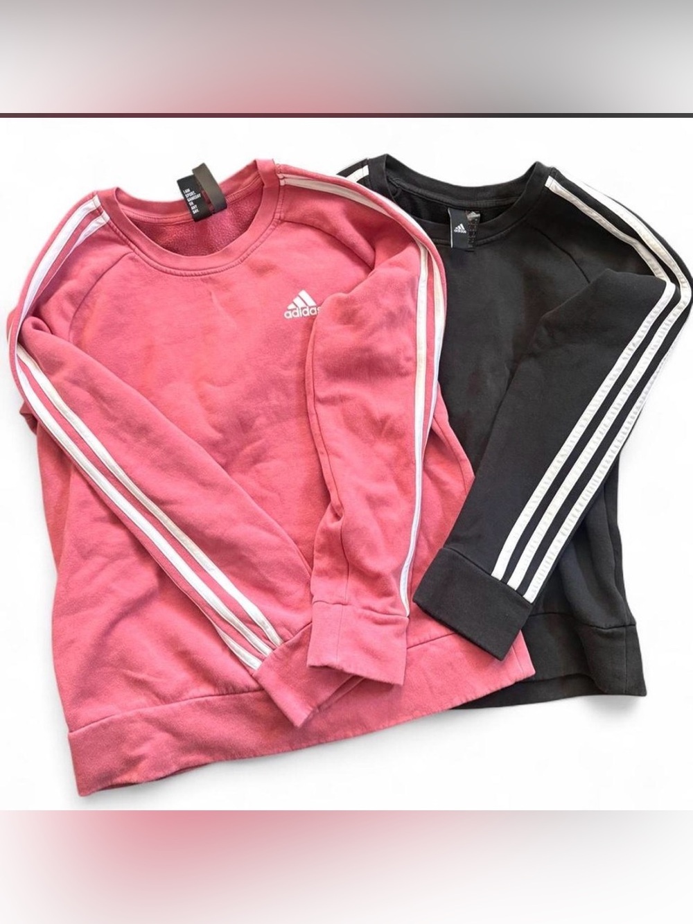 2 pairs of Adidas crewneck sweatshirts in pink and black with white stripes.